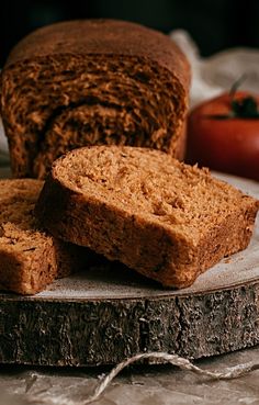 two pieces of bread sitting on top of a cutting board next to tomatoes and a knife