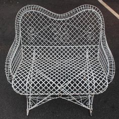 a white wire chair sitting on top of a parking lot