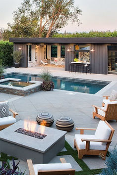 an outdoor fire pit in the middle of a backyard with chairs and tables around it