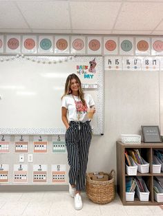 a woman standing in front of a whiteboard with writing on it and holding a cup