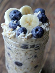 a jar filled with oatmeal and blueberries on top of a wooden table