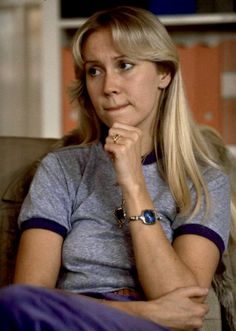 a woman sitting in a chair with her hand on her chin