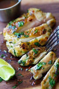 a close up of chicken on a cutting board with a knife and fork next to it