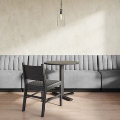 a table and chair sitting in front of a gray couch on top of a hard wood floor