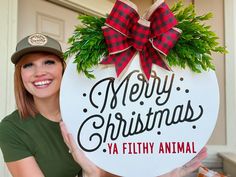 a woman holding up a merry christmas sign in front of a door with the words, ya filthy animal