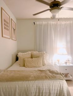 a bedroom with a bed, ceiling fan and two pictures on the wall above it