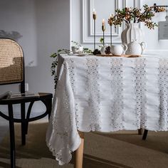 a white table cloth with lace on it next to a chair and potted plant