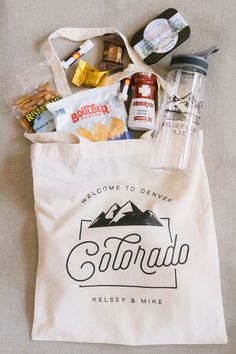 a tote bag filled with snacks and condiments sitting on top of a bed