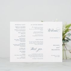 a wedding program card with flowers in the background