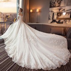 a woman in a wedding dress is standing near a window looking out at the city