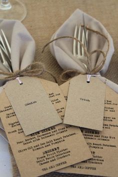 four pieces of paper with tags attached to them sitting on a table next to silverware