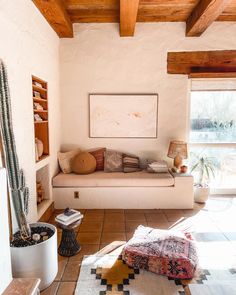 a living room filled with furniture and a large window covered in wood planked beams