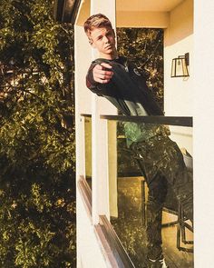 a man standing on the outside of a house looking at his reflection in the window