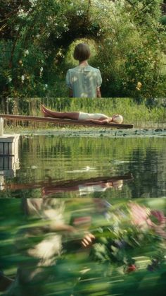 a person sitting on the edge of a body of water with flowers in front of them