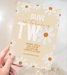 a person holding up a card with the words olive is turning two in front of them