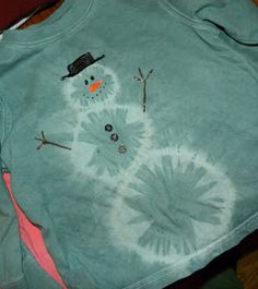 a blue shirt with a snowman drawn on the front and back, sitting on top of a table