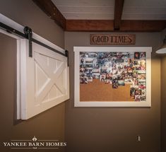 a barn door is open in front of a bulletin board with pictures hanging on it