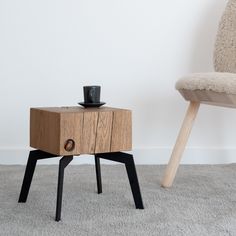 a wooden table with a cup on it and a chair in the corner behind it