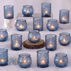 many blue glass jars with lit candles in them