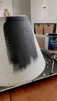 a black and white lamp shade sitting on top of a wooden table next to a paint roller