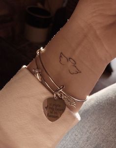 a person wearing a bracelet with a heart on it and a small dog tag attached to the wrist