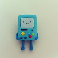 a blue toy with a smile on it's face and arms, sitting on a white surface