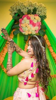 a woman with henna on her hands and arms in front of a green backdrop