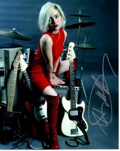 a woman sitting on top of a table next to guitars and amps in front of her