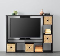 a flat screen tv sitting on top of a wooden entertainment center filled with drawers and baskets