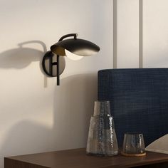 two vases sit on a table next to a wall light