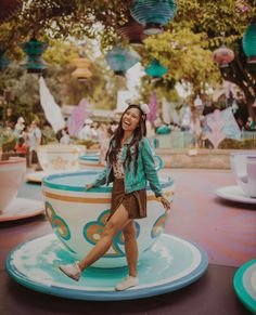 a woman standing on top of a teacup in front of some paper lanterns hanging from the ceiling