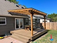 a wooden deck with a picnic table on it next to a fenced in backyard