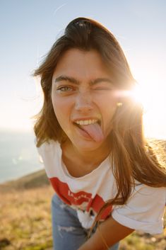 a woman sticking her tongue out in front of the camera on top of a hill