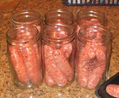 several jars filled with hot dogs sitting on top of a counter