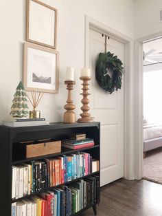 a book shelf filled with books in front of a door and wreath on the wall