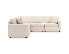 a white sectional couch with pillows on the top and bottom corner, facing away from the camera