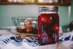 a jar filled with red liquid sitting on top of a blue and white striped towel