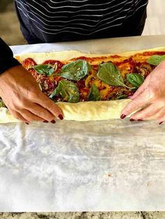 a person holding a pizza in their hands on top of a table with some dough