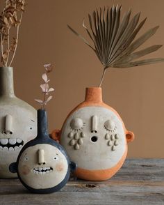 three ceramic vases with faces and plants in them