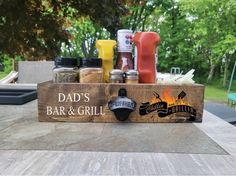 a wooden sign that says dad's bar and grill with spices in it on a picnic table