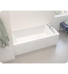 a white bathtub sitting next to a window in a bathroom with towels hanging on the wall