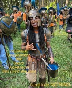 a woman dressed in armor and holding two buckets while standing next to other people