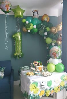 a birthday party with balloons and jungle animals on the wall, including an animal balloon arch