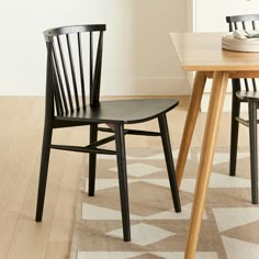 two black chairs sitting on top of a wooden floor next to a dining room table