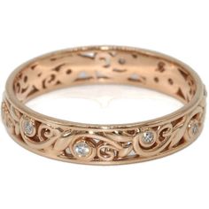 a rose gold wedding ring with diamonds on the sides and an intricate design in the middle