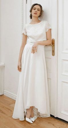 a woman standing in front of a door wearing a white dress