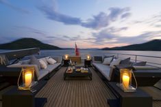 an outdoor lounge area on the deck of a boat at dusk with candles lit up