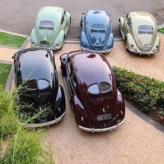 four different colored cars are parked in a parking lot next to each other on the sidewalk