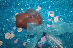 a chocolate heart shaped lollipop on a blue background with confetti around it