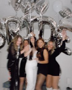 a group of women standing next to each other in front of foil letters and balloons